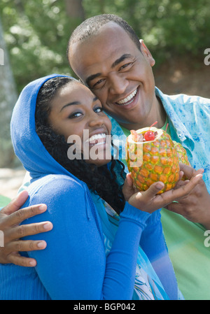 Portrait of a mid adult man and a young woman holding a pineapple and smiling Stock Photo