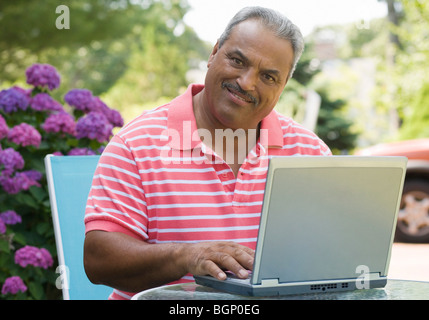 Portrait of a senior man using a laptop and smiling Stock Photo