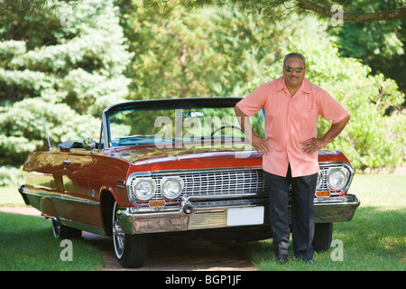 Senior man standing in front of a convertible car in a park Stock Photo