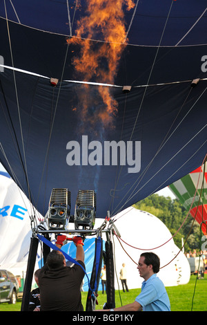 Balloonist pilot blowing hot air in balloon with propane burners for take-off during hot-air ballooning meeting Stock Photo