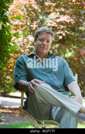 Portrait of a mature man sitting on a chair and smirking Stock Photo