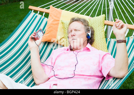 High angle view of a mature man listening to music and lying in a hammock Stock Photo