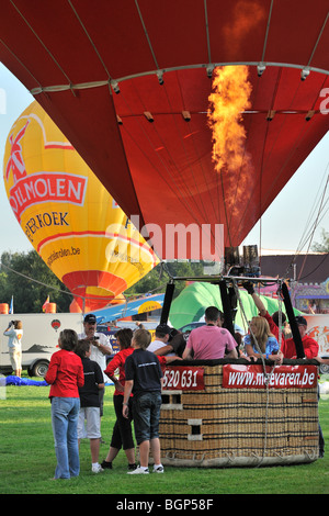 Hot air balloonists / Aeronauts preparing and inflating hot-air balloon with propane burners during ballooning meeting, Belgium Stock Photo