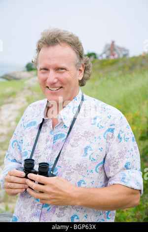 Portrait of a mature man holding a pair of binoculars Stock Photo
