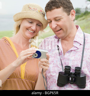 Mid adult woman standing with a mature man and holding a digital camera Stock Photo