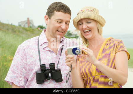 Mid adult woman standing with a mature man and holding a digital camera Stock Photo