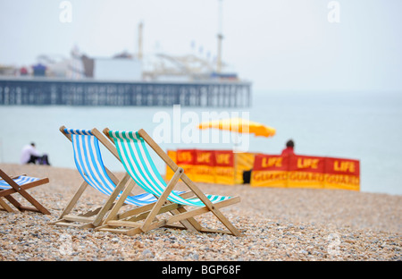 Beach safety on Brighton beach in East Sussex. Deck chairs on the beach with a life guard station in the distance. Stock Photo