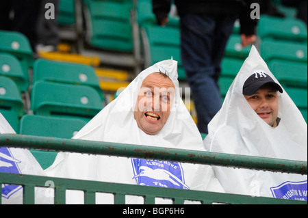 Heavy rain sees these two dedicated football supporters wearing pyramid shaped plastic bags to keep dry at Brighton. Stock Photo