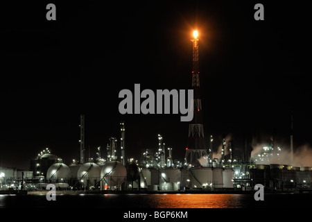 Pylon with burning gas flame at oil refinery from the petrochemical industry at the Antwerp harbour at night, Belgium Stock Photo