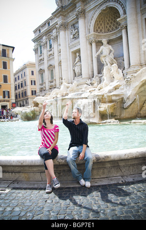 Young couple throwing a coin in the Trevi Fountain in Rome, Italy Stock Photo