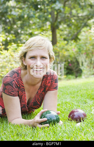 Portrait of a mature woman lying on grass and holding a croquet ball Stock Photo