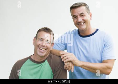 Portrait of a mature man leaning on his brother's shoulder and smiling Stock Photo