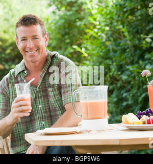 Portrait of a mature man holding a glass of juice and smiling Stock Photo