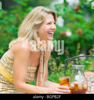 Side profile of a mature woman sitting at a table and drinking ice tea Stock Photo
