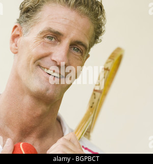 Portrait of a mature man holding a tennis racket and a tennis ball Stock Photo