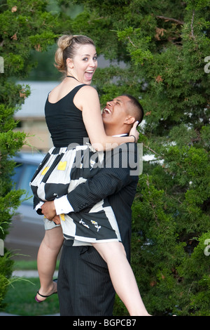 A man in a suit lifts his wife into the air. Stock Photo
