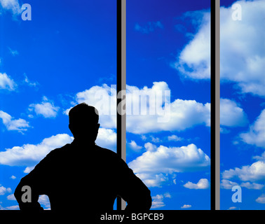 man looking at clouds through large glass window Stock Photo