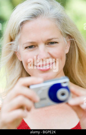 Close-up of a mature woman taking a picture with a digital camera Stock Photo
