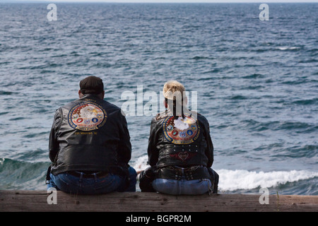 American bikers couple sitting on a shore lake Harley Davidson attire clothes clothing U.S.lifestyle from behind back scenic people in USA hi-res Stock Photo