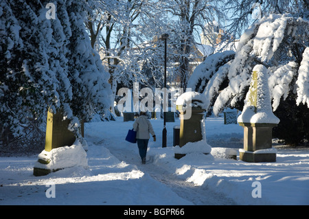 Winter January 2010 Scotland - Kelso Scottish Borders. Woman walking through churchyard to shops. Stock Photo