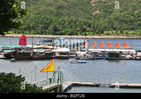 Junks and fishing boats moored alongside a floating fish farming pier with flying flags, Sok Kwu Wan, Lamma Island, Hong Kong Stock Photo