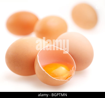 With brown eggs on a white background. One egg is broken. Stock Photo