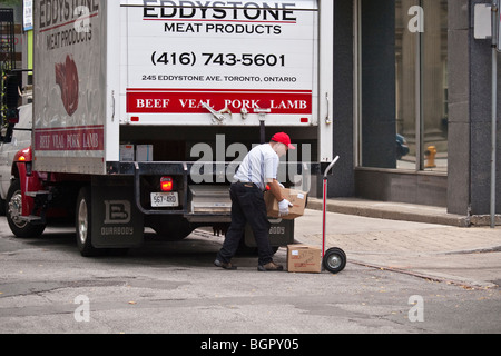 Man on delivery, loading a dolly with boxes, meat products, Toronto, Canada Stock Photo