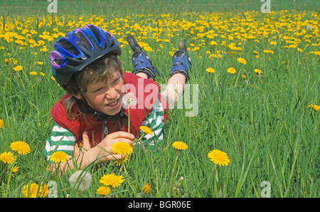 portrait of a young skater resting on a meadow looking at dandelions Stock Photo