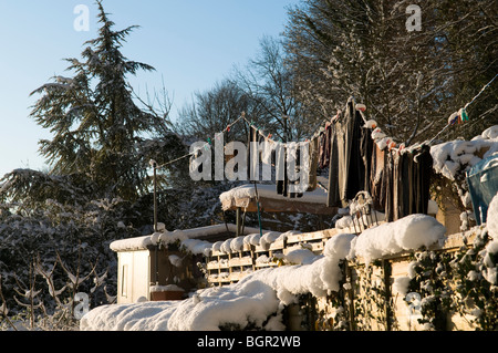 Snow-covered clothing hung out to dry on a clothes line Stock Photo
