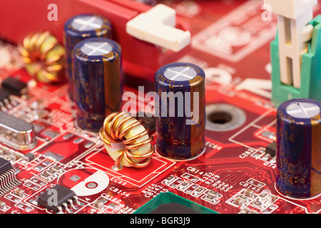 Close up of electronic components on a red circuit surface Stock Photo