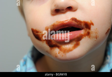 young child blond boy with chocolate smeared all over face Stock Photo