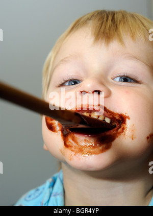 young child blond boy with chocolate smeared all over face Stock Photo