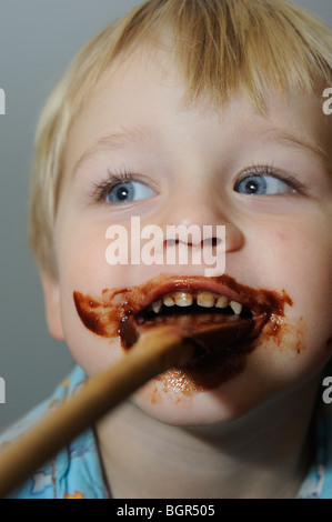 young child blond boy with chocolate smeared all over face Stock Photo