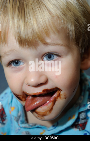 young child blond boy with chocolate smeared all over face Stock Photo