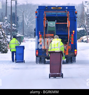 Dustcart lorry and binmen on icy snow covered residential road Stock Photo