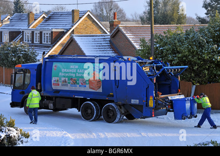 Dustcart lorry and binmen on icy snow covered residential road LA details digitally removed Stock Photo