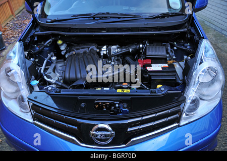 Under the bonnet close up of a blue Nissan Note hatchback motor car showing a petrol engine compartment England UK Stock Photo