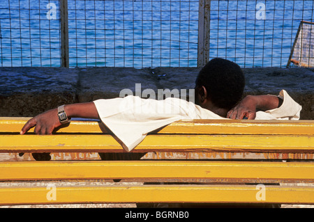 man with wrist watch lying on a yellow bench in Alexandria Egypt Northern Africa Stock Photo