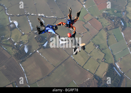 Three skydivers in free fall with snow in the background
