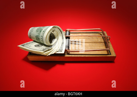 A roll of money sitting on an armed wooden mousetrap