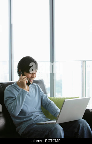 Young man talking on phone and working on laptop Stock Photo