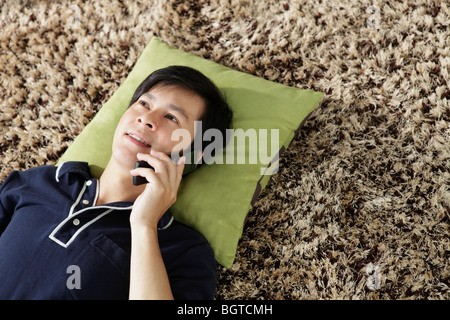 Young man lying on floor talking on phone Stock Photo