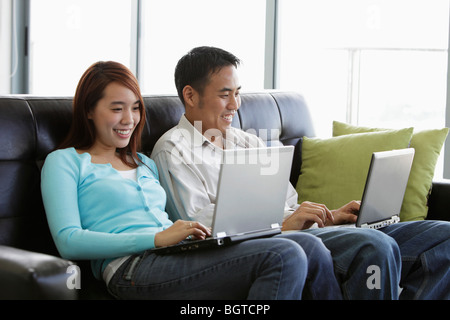 Young couple working on laptops and smiling Stock Photo