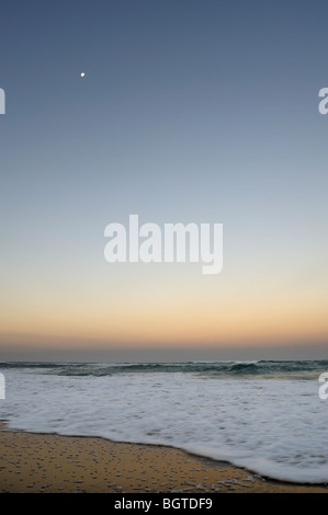 Moon over the shoreline of the Indian Ocean at dusk, Main Beach, St Lucia, Kwazulu-Natal, South Africa Stock Photo