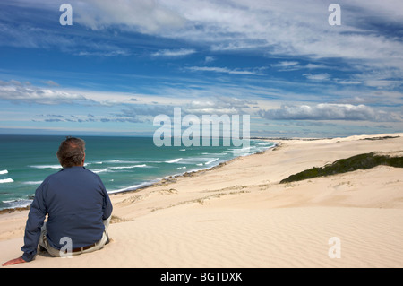 Rear view of a senior man sitting on sand dune,  De Hoop Nature Reserve, Western Cape , South Africa Stock Photo