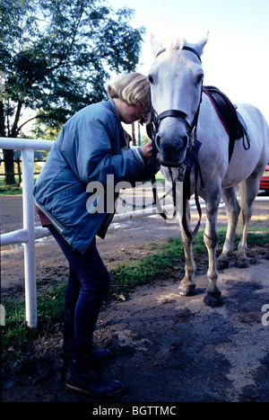 Horse rider attaching bridle on horse Stock Photo