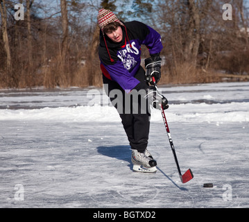 Teenage boy playing hockey on a frozen pond Stock Photo