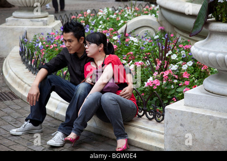 Young Asian couple relaxing together in Leicester Square, London. There are many Chinese in this area as it is near to Chinatown Stock Photo