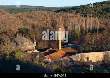 Chimney of disused paper factory and a castle, Brissac, Herault, France Stock Photo