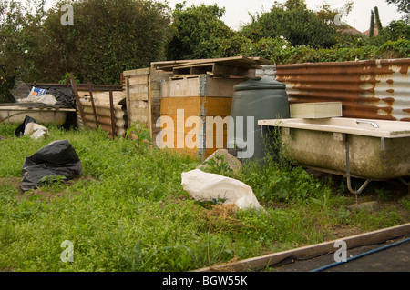 Composting area of an allotment plot showing various compost bins and old household baths being used for rainwater collection Stock Photo